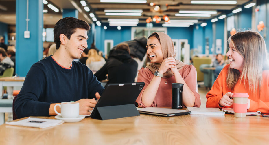 3 students sat at a table chatting together