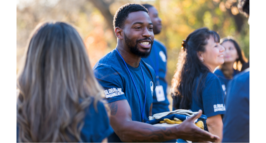 A young black man in a blue shirt talking to a group of people