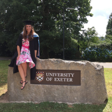 Student sat next to the University of Exeter sign