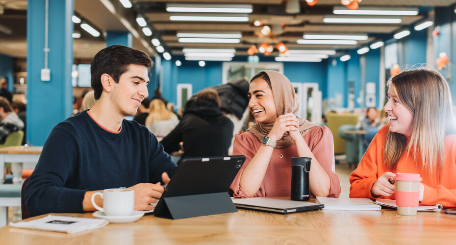 3 students sat at a table chatting together