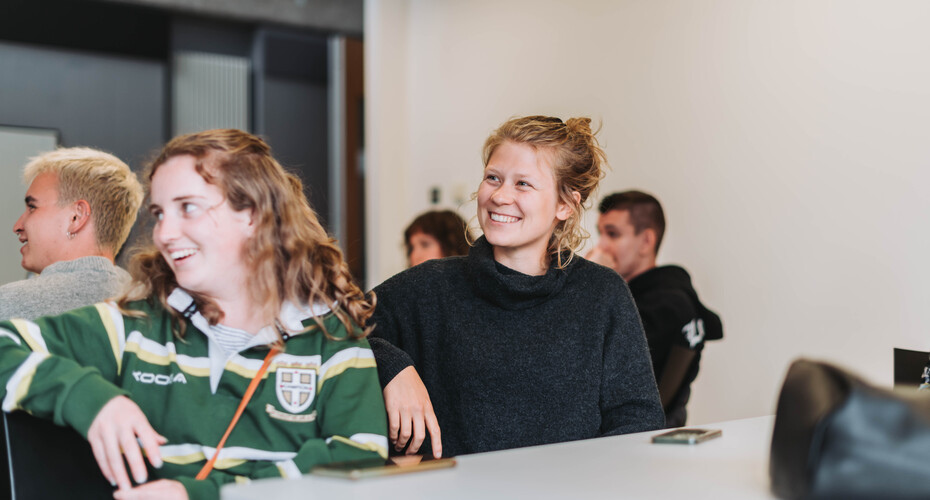 2 students sat at a table listening