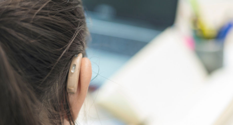 A student with a hearing aid in her ear, showcasing assistive technology for hearing enhancement.