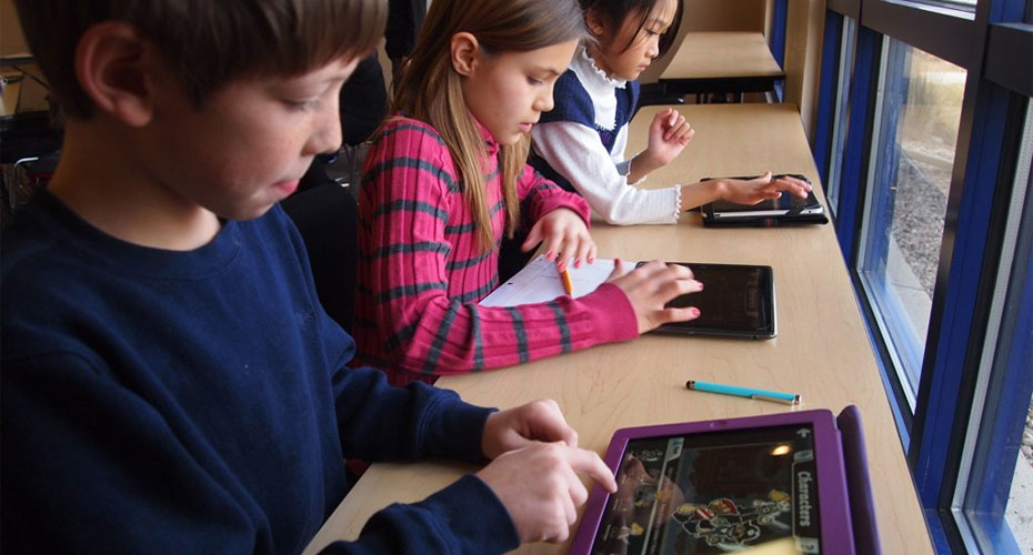 Three children on a bench with ipads