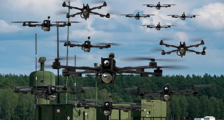 a military landscape with a variety of drones in the blue sky above a large vehicle.