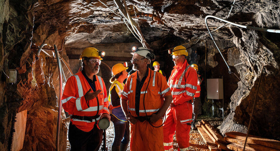 A group of mining students working together in a mine, wearing hi-vis and helmets