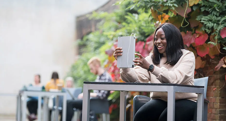 A student on an online course having a telephone chat via a tablet