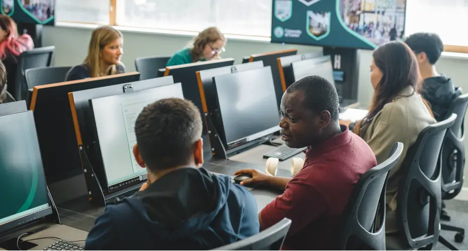 Two students in discussion sat next to each other in the computer science lab