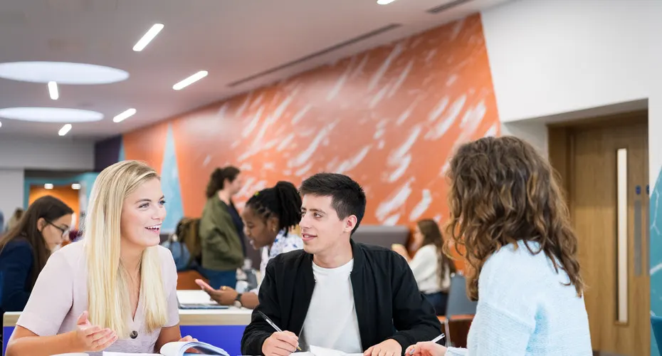 Students working in a group in front of an orange background