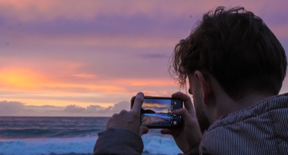 Man taking a photo of a sunset by the sea