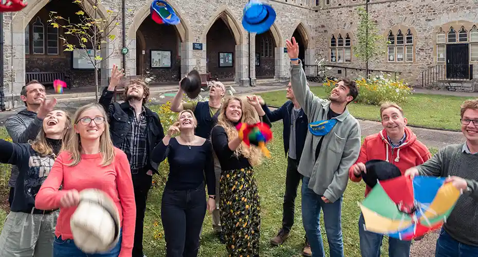 A group of students throwing colourful hats in the air at one of our Open Days