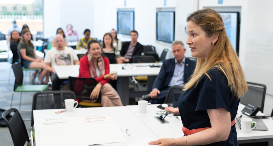 Female leading a session with a group of academics