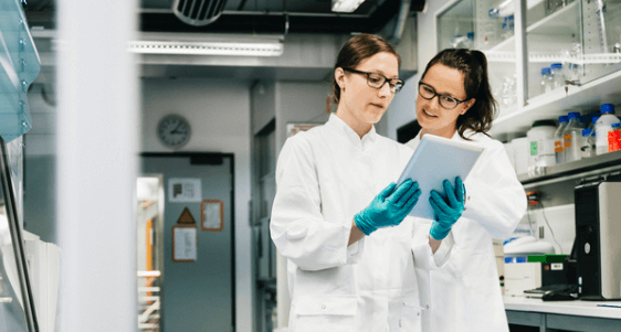 Two female scientists looking at ipad in lab