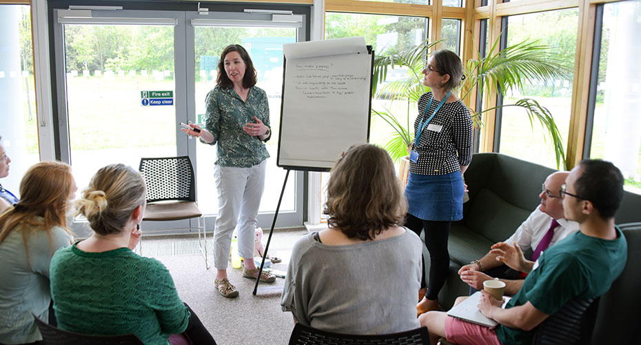 A woman presenting to a group of people in a conference room.