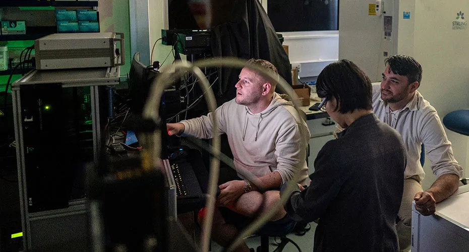 Three scientists studying information on a computer in a laboratory.