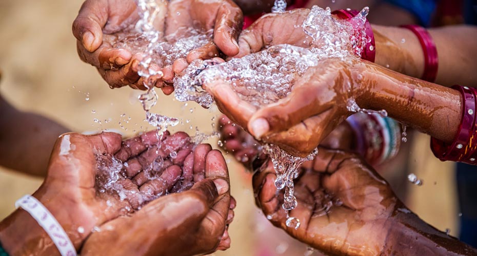 Clean water runnning through a group of people's hands