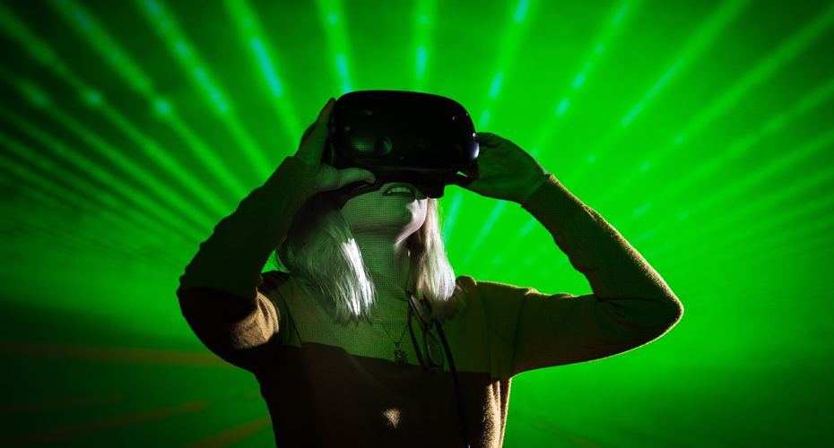 A student wearing a VR headset in front of a green graphic background