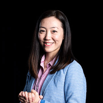 Dr Mi Tian photographed against the dark background in studio lighting