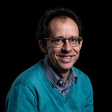 Professor Toby Pennington photographed in studio lighting against black background.