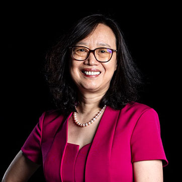 Professor Zhongdong Wang on a dark background under studio lights; she is smiling broadly