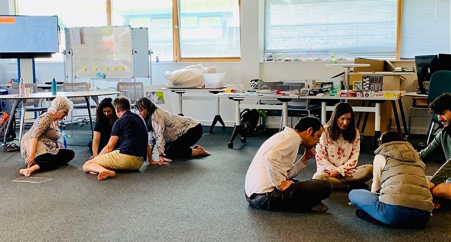 A diverse group of individuals sitting on the floor in a classroom at the innoplay studio workshop.