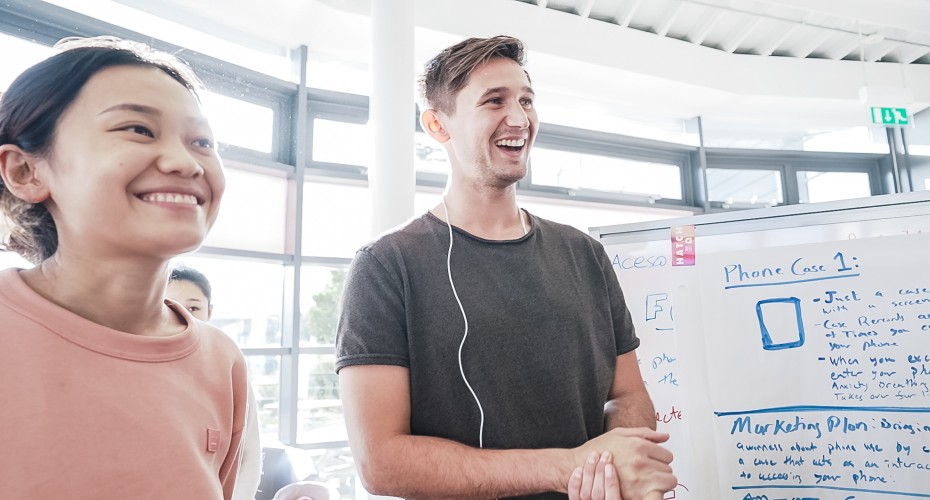 Two individuals in front of a whiteboard, symbolising a successful collaboration.