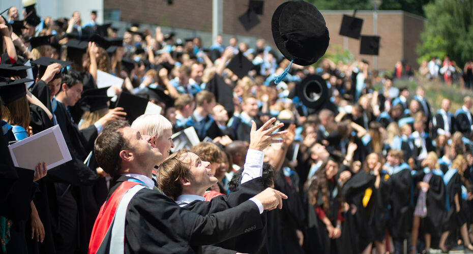 phd student throwing hat with whole cohort on steps outside Great hall in exeter