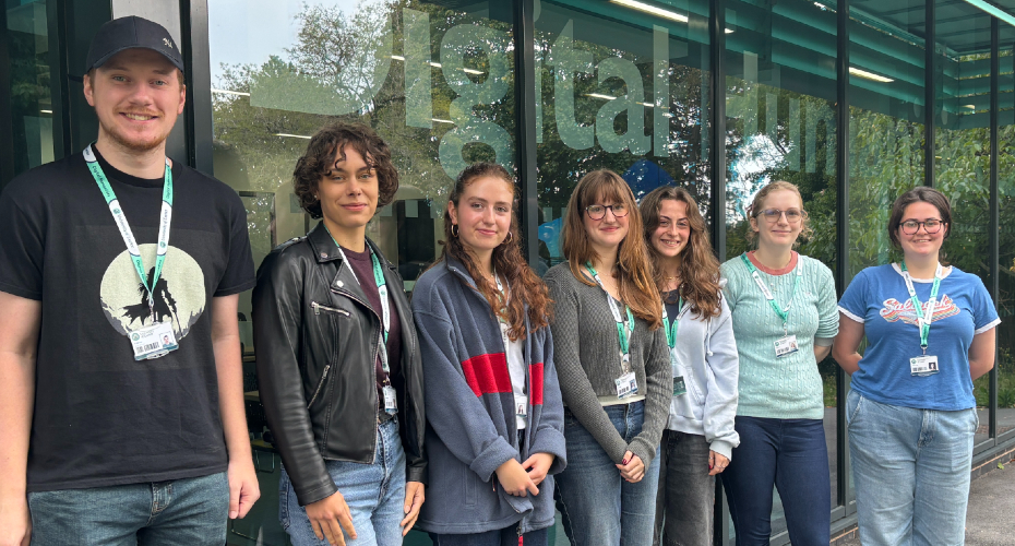 A group of 7 students standing in front of the digital humanities lab