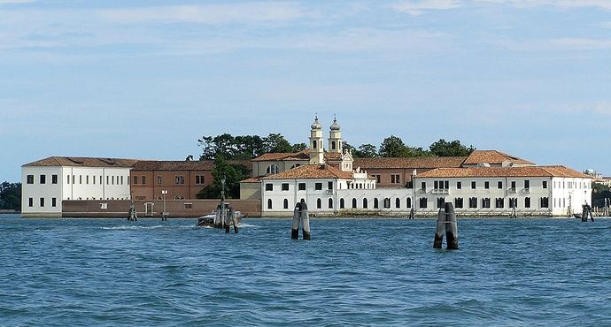 A large building with a white roof, featuring the san servolo island museum and venice international university in the background.