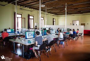 Several people focused on their computers, engaged in teamwork within a well-lit workspace.