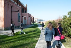 Individuals walking on a path next to a building, capturing a moment of daily life in a bustling area.