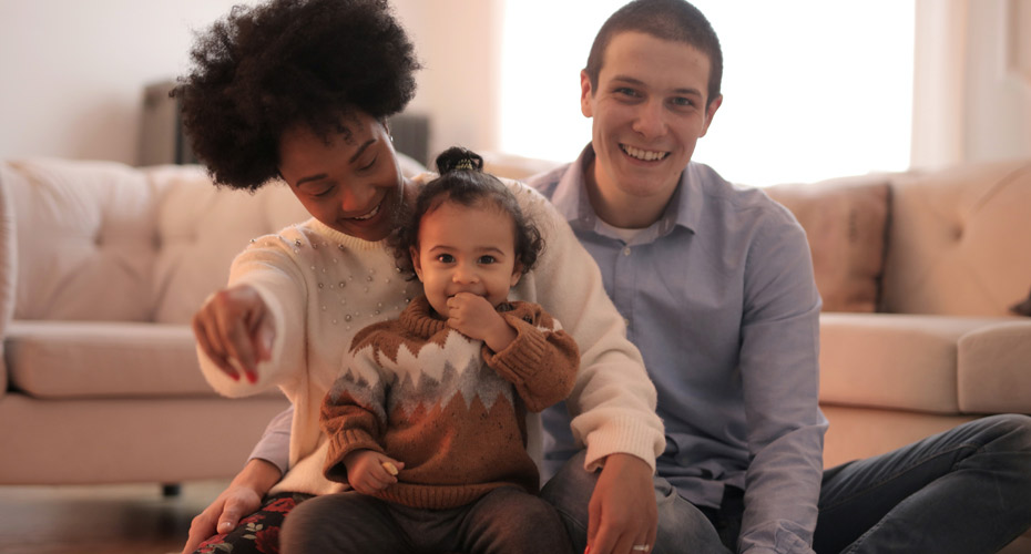 Husband and wife sat on floor cuddling their toddler