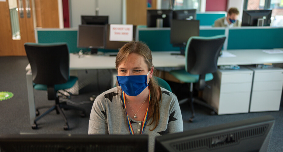 Person in a mask working at a laptop