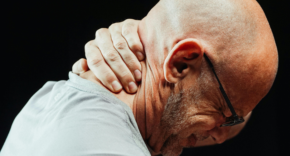 Man holding back of neck, grimacing in pain.