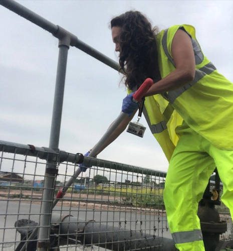 Daisy Harley-Nyang collecting sludge, wearing a hi-vis suit