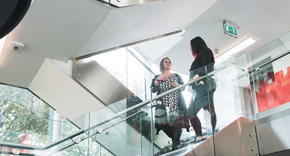 Two individuals ascending a staircase within a modern office building, showcasing a professional environment.